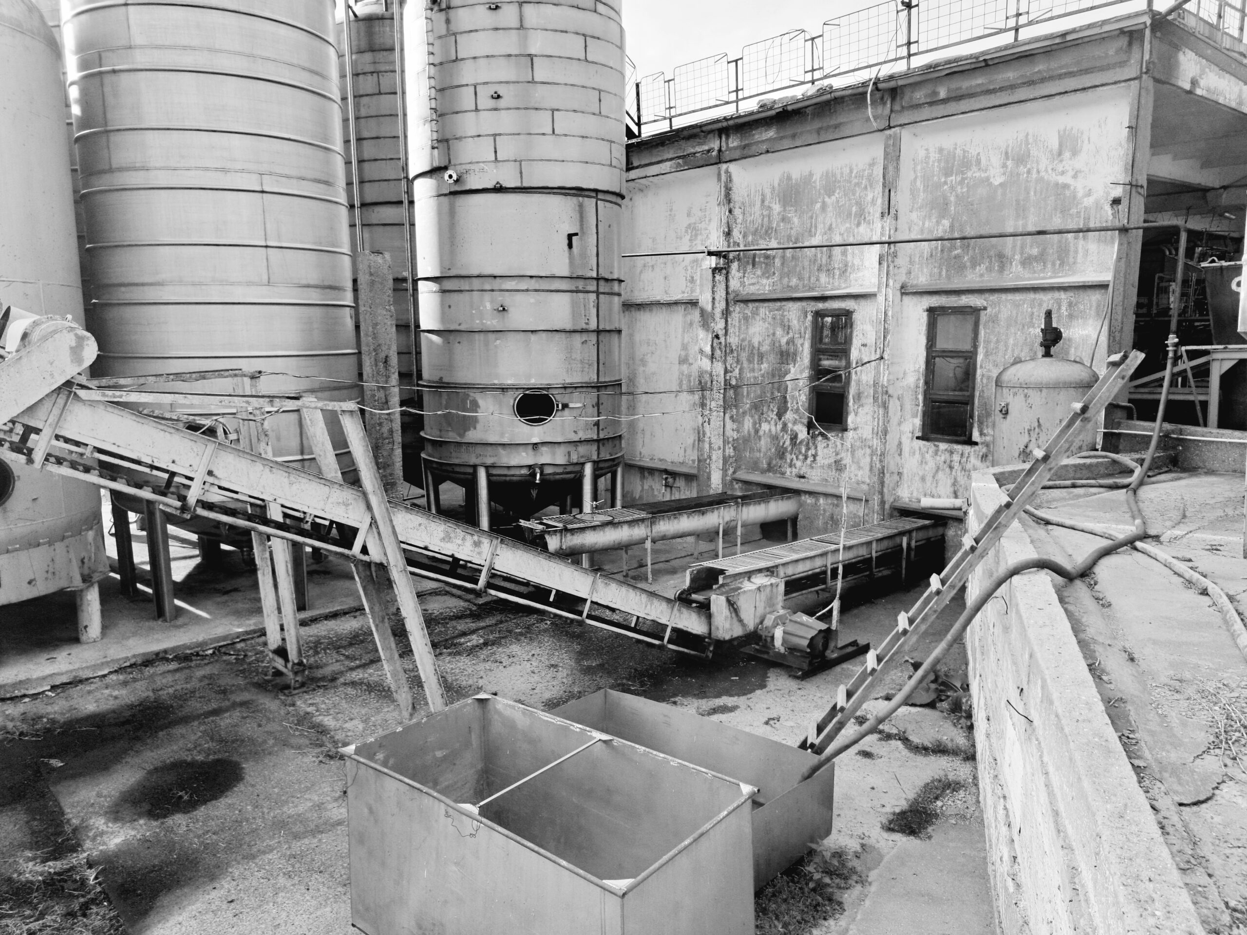 Black and white photo of an industrial warehouse featuring large silos and machinery.
